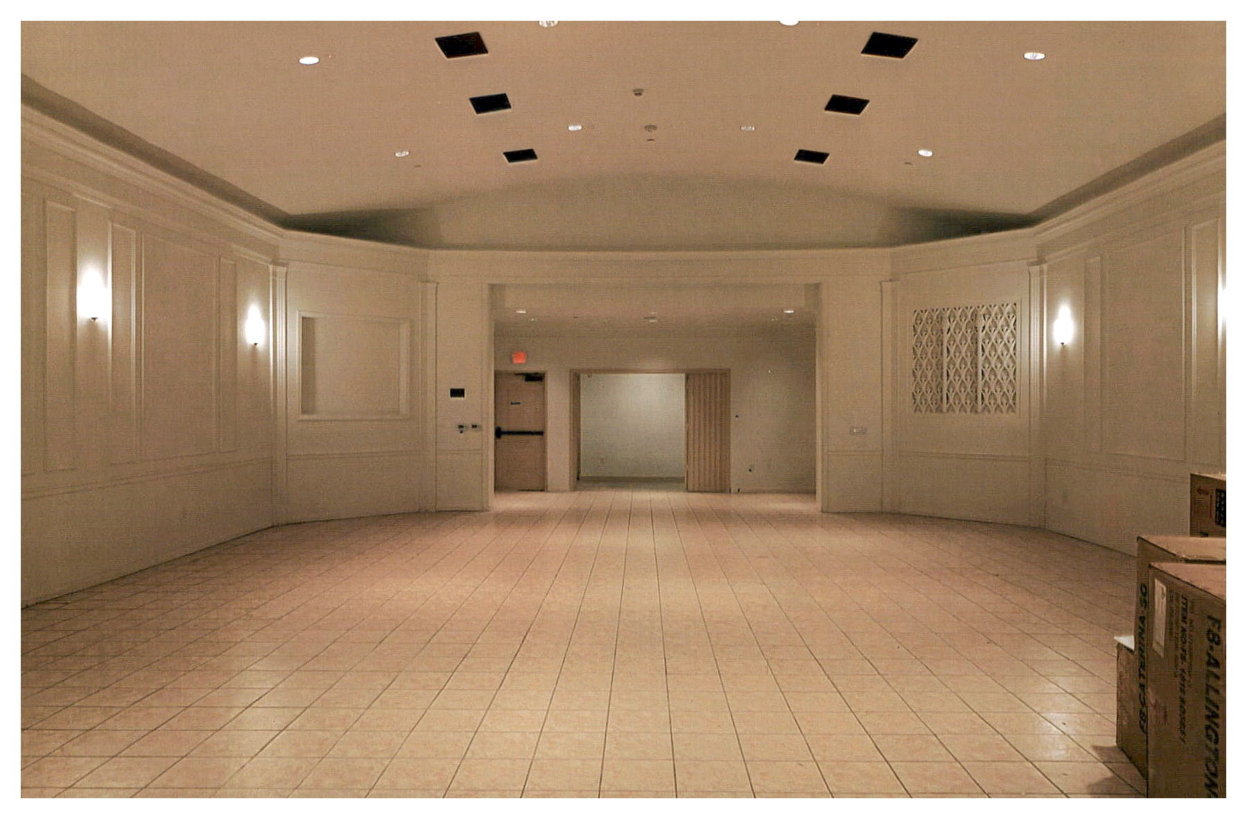 After: large community space with restored tile floor, new wall sconce light fixtures and new recessed lighting in slightly arched ceiling.