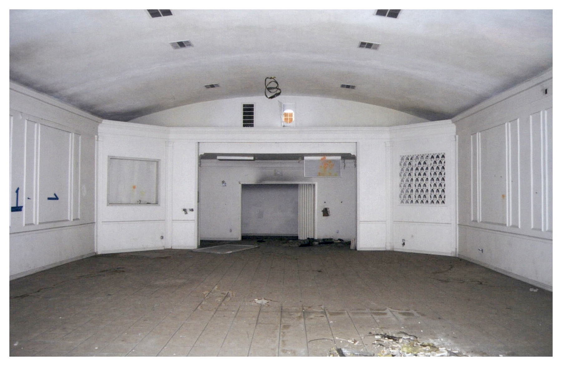 Before: same view of community room with dirty white walls and no lighting fixtures.