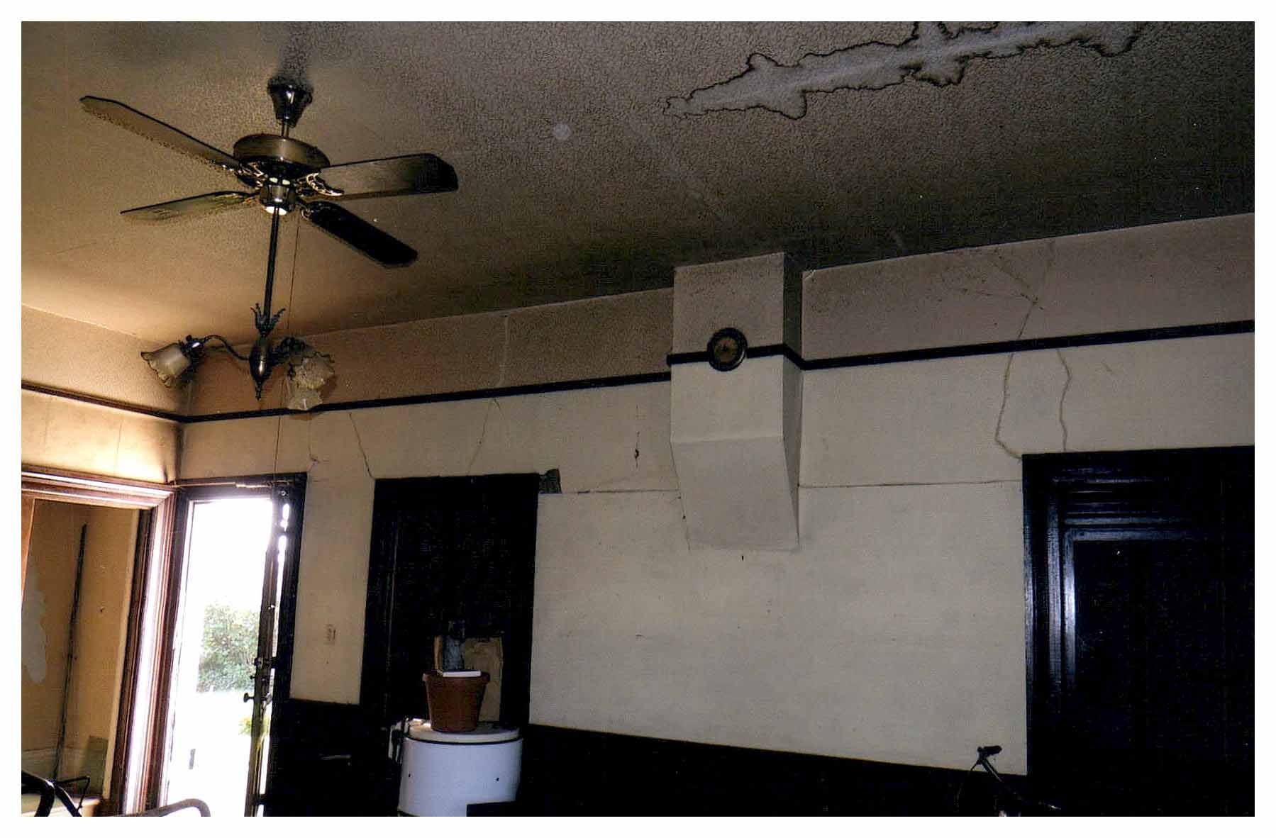 Before: same view of dining room showing cracked plaster, stained ceiling and a protruding flue which was removed.