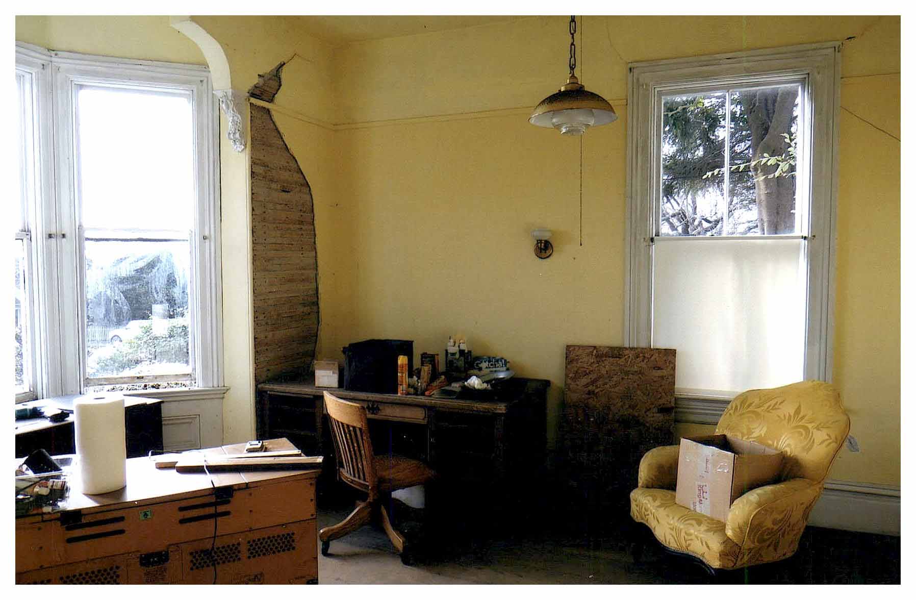 Before: same view of room with yellow painted walls and missing plaster.