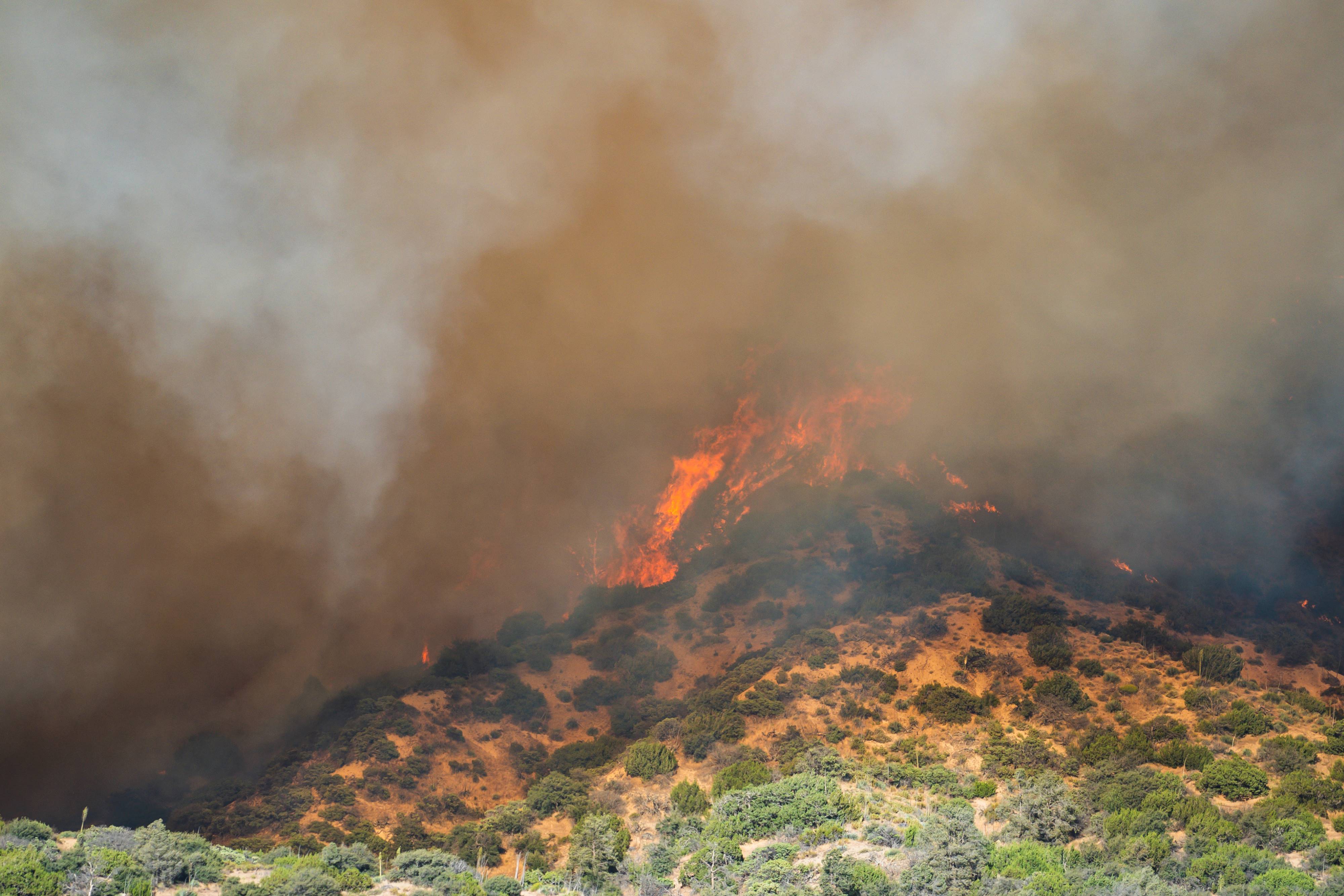 Fire burning a hilltop covered in smoke.