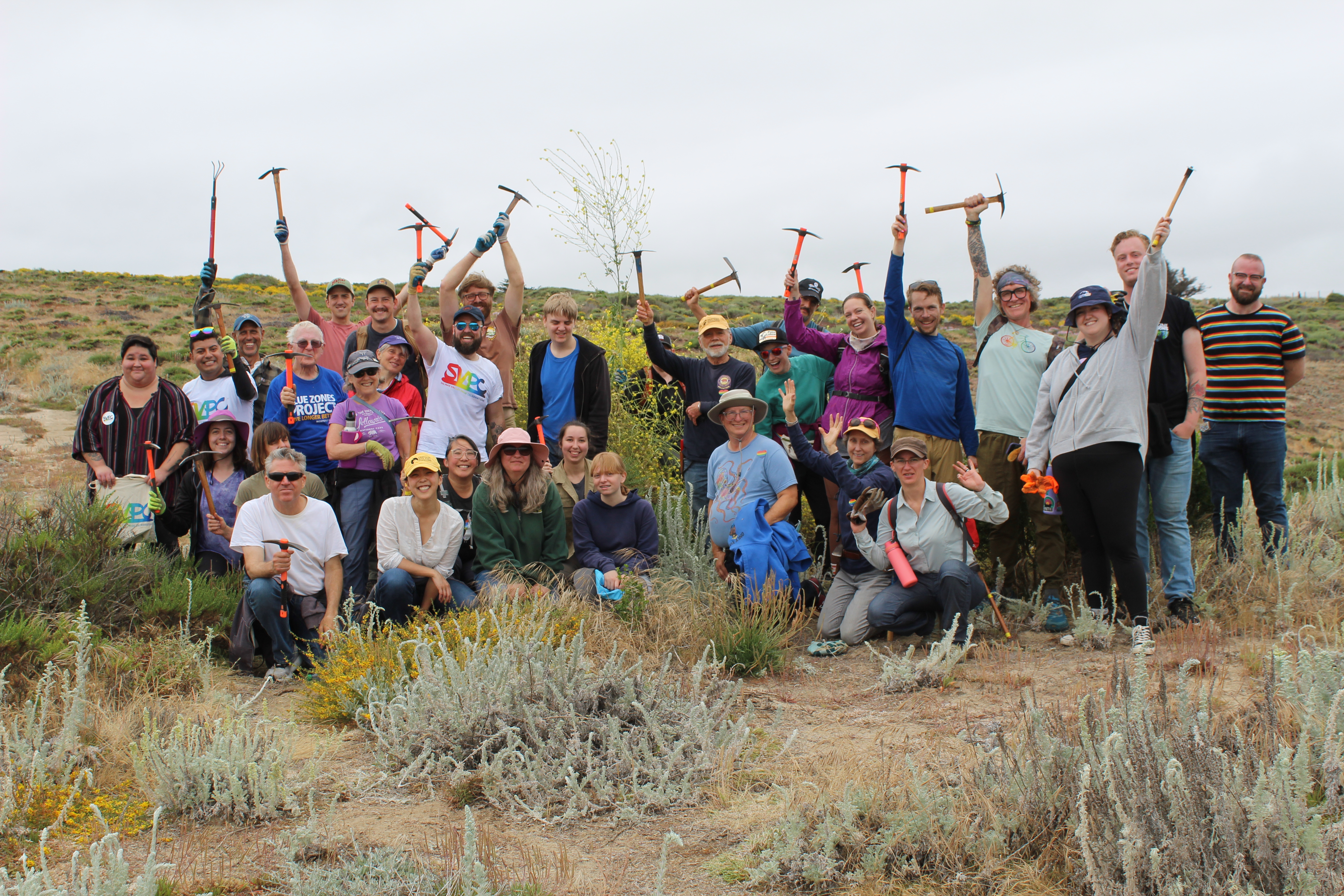 A group of volunteers pose with their hand tools after a morning of removing invasive mustard at Fort Ord Dunes State Park.