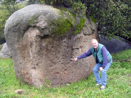 John Foster, Senior State Archaeologist, pointing to "cupples" in the rock.