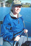 Here is a West Marine Jacket Contest winner in her blue jacket st the wheel of her boat.