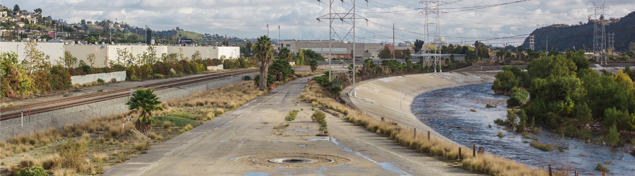 The Bowtie looking south. A small, paved road with railroad tracks on the left and the Los Angeles River on the right.