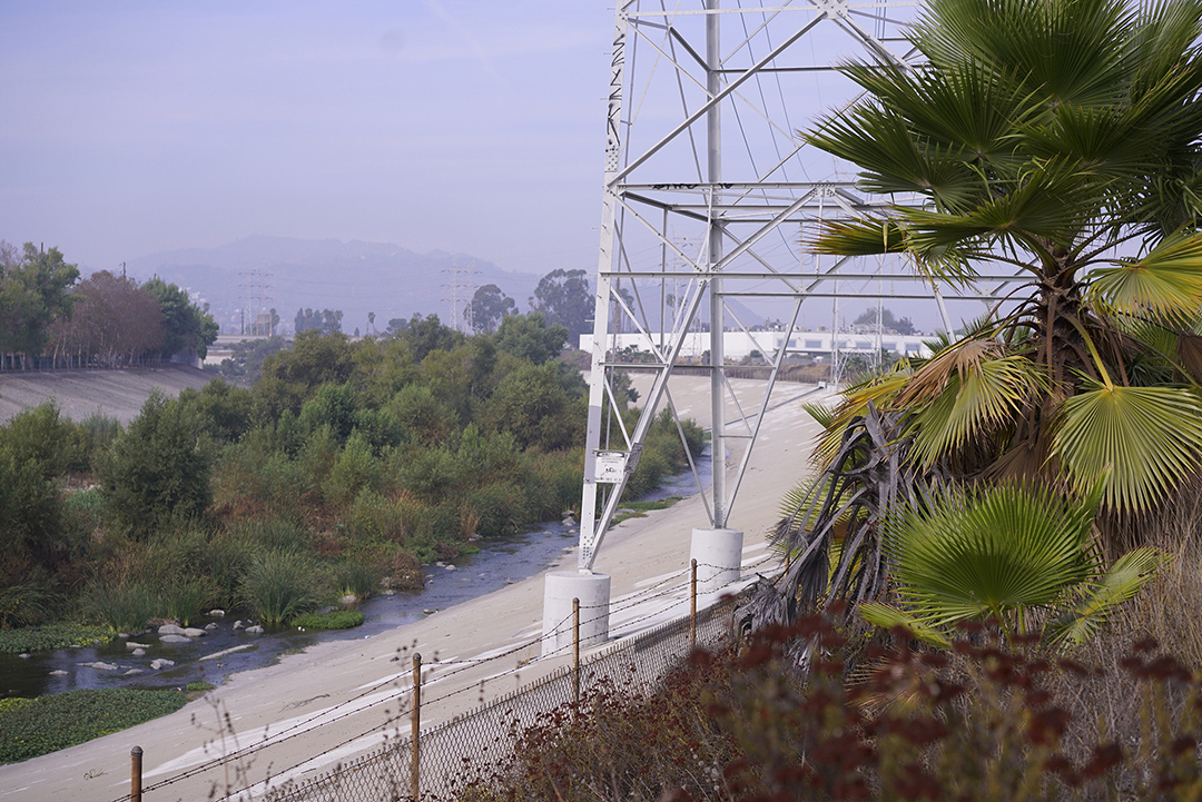 The Los Angeles River at the Bowtie with concrete embankments and vegetation in the riverbed. The Los Angeles River at the Bowtie with concrete embankments and vegetation in the riverbed.