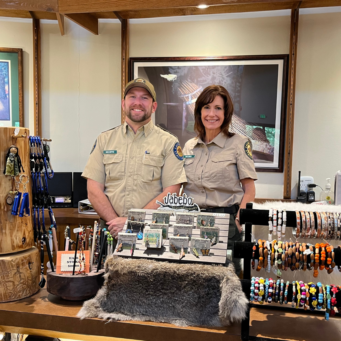 Two California State Parks staff in uniform standing behind the museum counter 