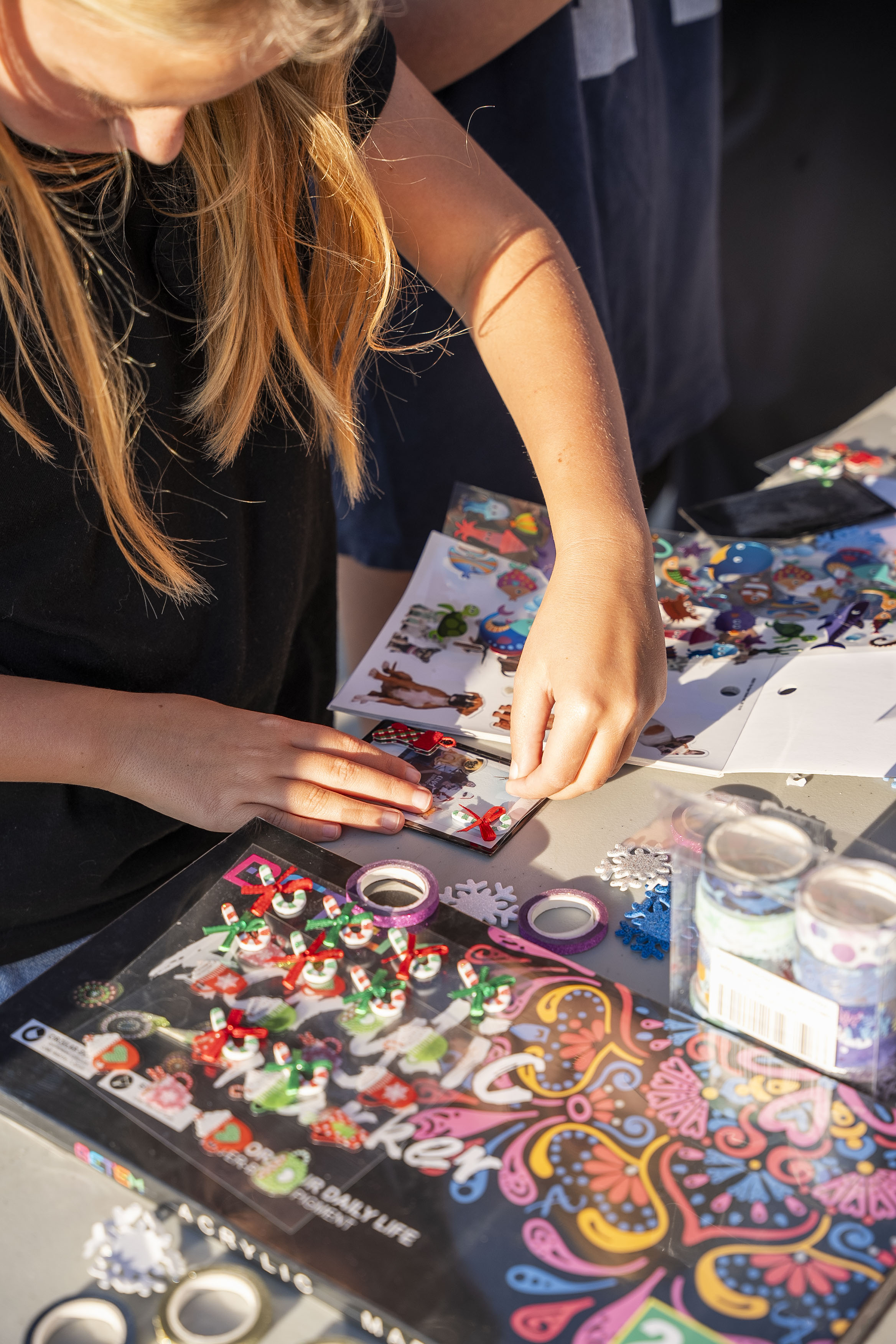 A young girl decorates a polaroid photo on a craft table.
