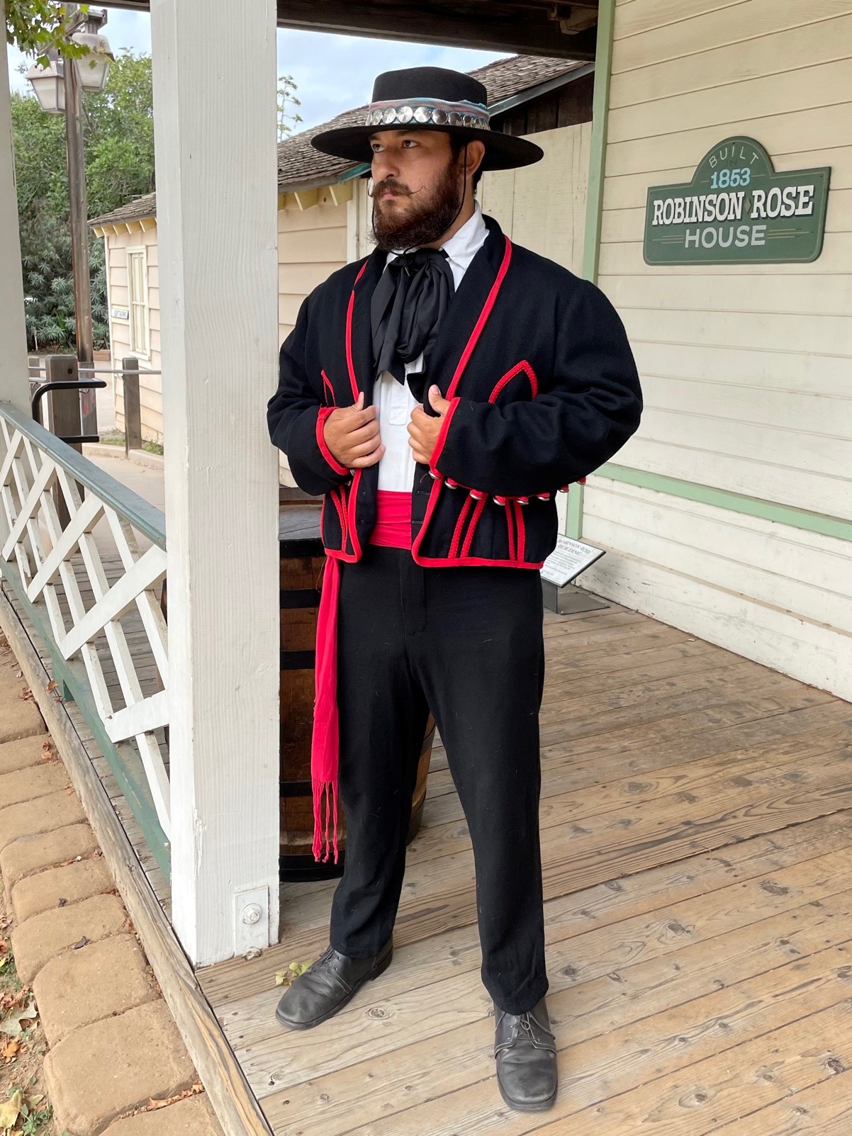 Photo of a man in black Californio attire with red trim and a white shirt
